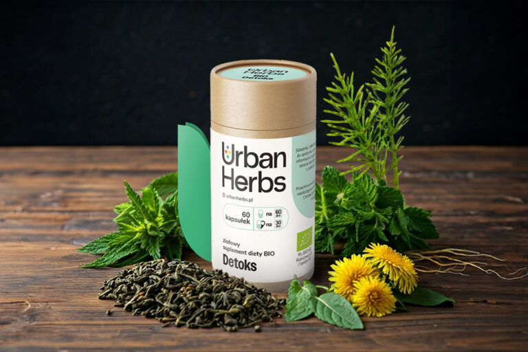 Opakowanie suplementów UrbanHerbs BIO Detoks w postaci papierowej tuby z papierową etykietą. Etykieta ma zamknięcie w kształcie odstającego listka. Jest otoczona roślinami.