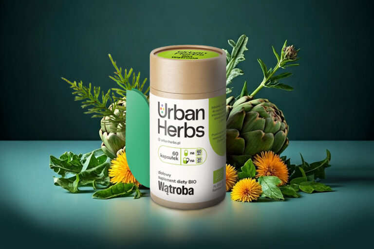 Opakowanie suplementów UrbanHerbs BIO Wątroba w postaci papierowej tuby z papierową etykietą. Etykieta ma zamknięcie w kształcie odstającego listka. Jest otoczona roślinami.